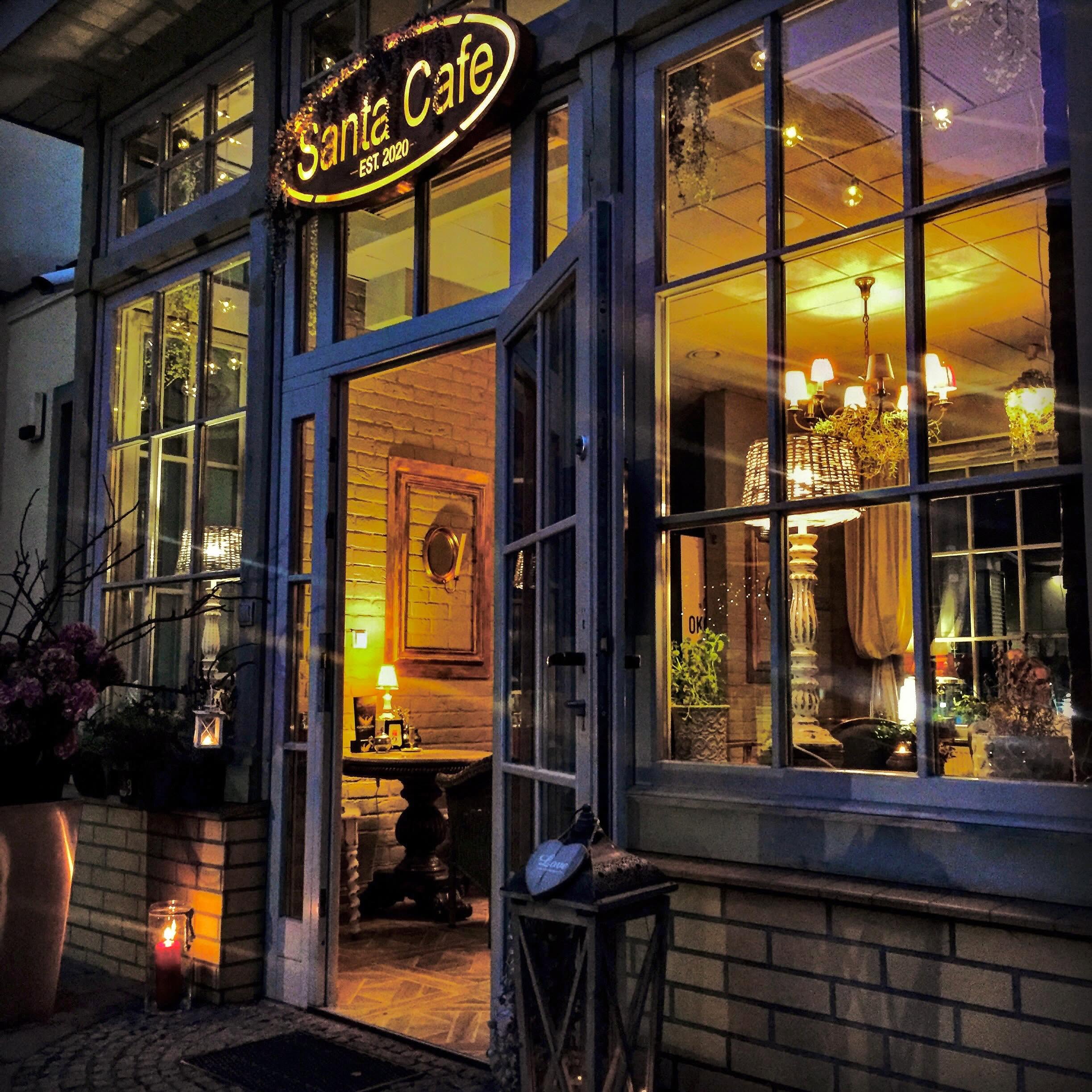 Oświetlone wejście do Santa Cafe z owalnym szyldem